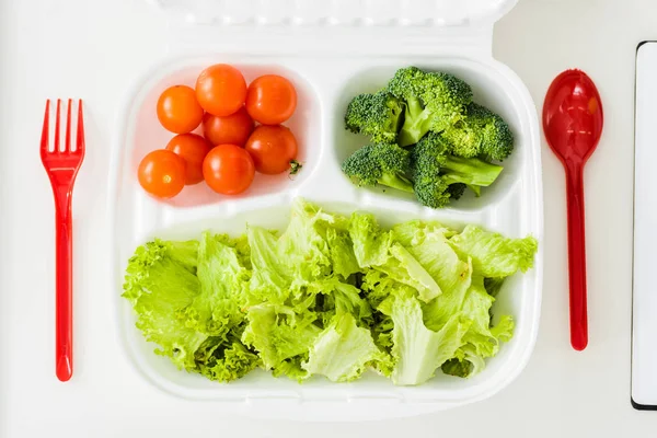 Top view of tasty organic vegetables near plastic fork and spoon — Stock Photo