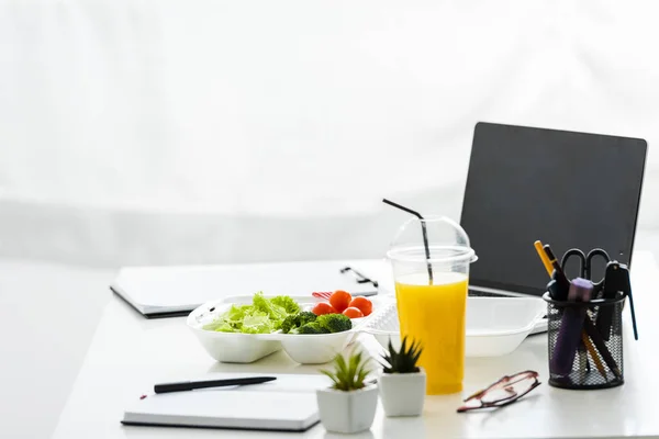 Take-away-Box mit leckerem Gemüse in der Nähe von Laptop mit leerem Bildschirm — Stockfoto