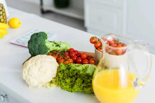 Органічні та смачні овочі біля глечика з апельсиновим соком — стокове фото