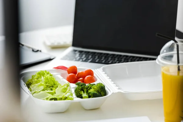 Levar caixa com vegetais orgânicos e saborosos perto de laptop com tela em branco — Fotografia de Stock
