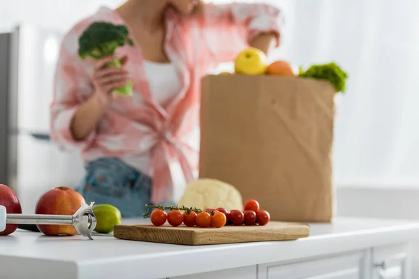 Селективный фокус нарезанной доски с помидорами черри рядом с женщиной — стоковое фото