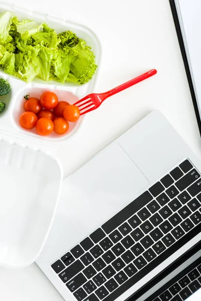 Top view of takeaway box with organic vegetables near laptop — Stock Photo