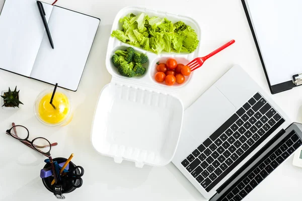 Top view of tasty vegetables near laptop and notebook with copy space — Stock Photo
