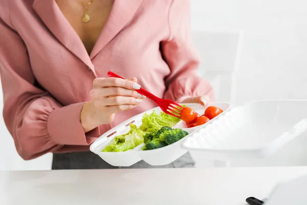 Vista cortada da mulher segurando caixa takeaway com vegetais orgânicos e garfo de plástico — Fotografia de Stock