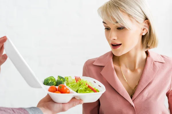 Cropped view of man holding takeaway box with vegetables near surprised young woman — Stock Photo