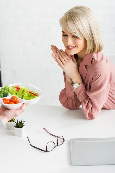 Cropped view of man holding takeaway box with vegetables near happy young woman — Stock Photo