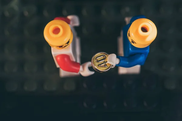 QUIIV, UCRÂNIA - MARÇO 15, 2019: vista superior da figura de lego subornando outra figura de lego com moeda de ouro — Fotografia de Stock