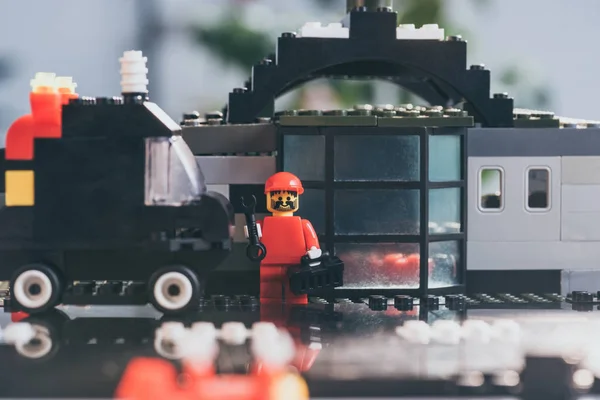 QUIIV, UCRÂNIA - MARÇO 15, 2019: figura de trabalhador de lego vermelho em chapéu segurando chave inglesa e caixa de ferramentas perto de carro de brinquedo — Fotografia de Stock
