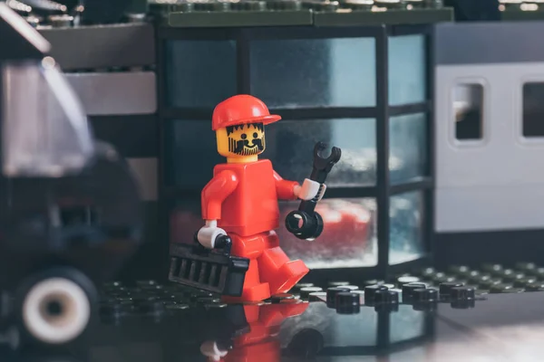 KYIV, UKRAINE - 15 MARS 2019 : figurine de travailleur lego rouge dans une clé à chapeau et une boîte à outils près d'un bâtiment en blocs de lego — Photo de stock