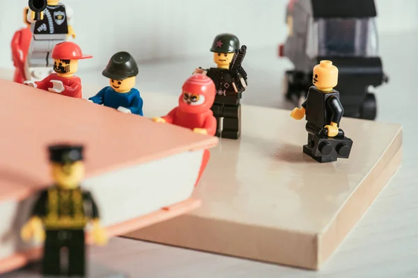 QUIIV, UCRÂNIA - MARÇO 15, 2019: foco seletivo de minifiguras de lego de plástico carregando livro perto de figuras de guarda — Fotografia de Stock