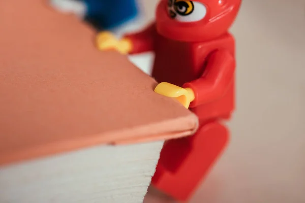 KYIV, UKRAINE - MARCH 15, 2019: close up view of red lego minifigure carrying book — Stock Photo