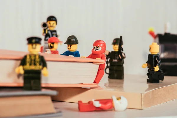 Київ, Україна-15 березня 2019: закрити вид пластикових LEGO мініфігурки, що перевозять книги біля гвардії цифри з пістолетом і мундштук — Stock Photo