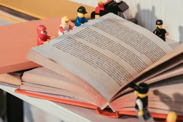 QUIIV, UCRÂNIA - MARÇO 15, 2019: foco seletivo de minifiguras coloridas de plástico lego virando página do livro — Fotografia de Stock