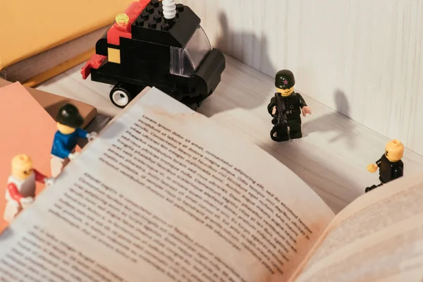 KYIV, UKRAINE - MARCH 15, 2019: colorful plastic lego minifigures turning page of book near toy truck — Stock Photo