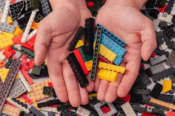 QUIIV, UCRÂNIA - MARÇO 15, 2019: visão recortada do homem segurando nas mãos blocos de lego coloridos — Fotografia de Stock