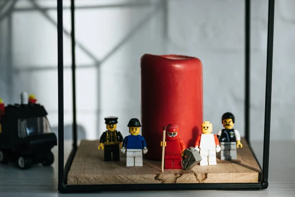 KYIV, UKRAINE - 15 MARS 2019 : figurine rouge avec boîte d'essence et match debout avec des personnages de lego près de la bougie — Photo de stock