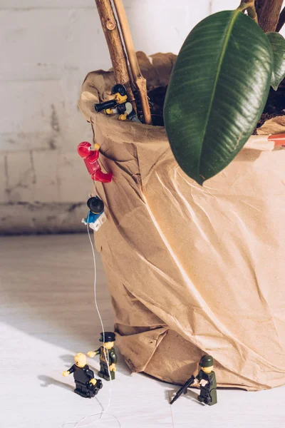 QUIIV, UCRÂNIA - MARÇO 15, 2019: policiais de brinquedo de pé com arma enquanto figuras de lego de plástico escalam planta com corda — Fotografia de Stock