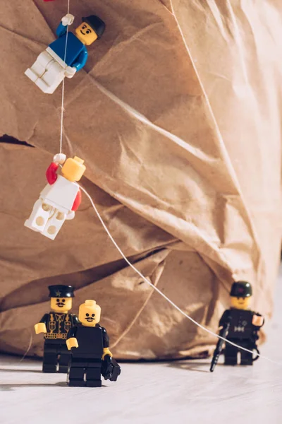 QUIIV, UCRÂNIA - MARÇO 15, 2019: policiais de lego de pé com arma enquanto figuras de lego de plástico escalando corda — Fotografia de Stock