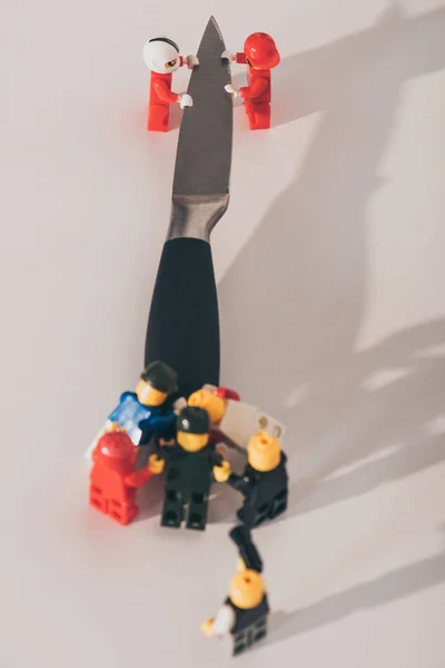 KYIV, UKRAINE - MARCH 15, 2019: close up view of plastic lego figurines carrying metal knife on white — Stock Photo