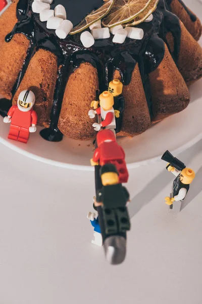 QUIIV, UCRÂNIA - MARÇO 15, 2019: minifiguras de plástico de lego cortando bolo com faca no branco — Fotografia de Stock