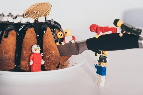 KYIV, UKRAINE - MARCH 15, 2019: plastic lego minifigures cutting cake with knife on white — Stock Photo