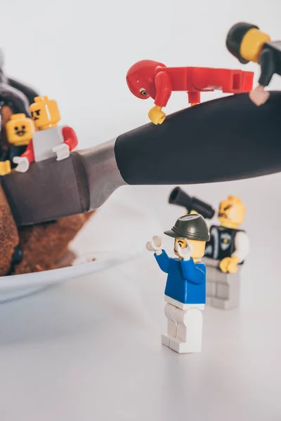 QUIIV, UCRÂNIA - MARÇO 15, 2019: close up view of plastic lego minifigures cutting cake with knife — Fotografia de Stock