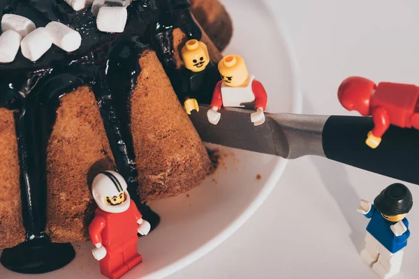 Kyiw, Ukraine - 15. März 2019: Lego-Minifiguren aus Plastik schneiden leckeren Kuchen mit Messer — Stockfoto