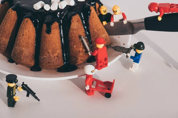 KYIV, UCRANIA - 15 DE MARZO DE 2019: minifiguras de lego de plástico cortando delicioso pastel con cuchillo - foto de stock