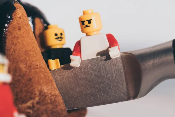 QUIIV, UCRÂNIA - MARÇO 15, 2019: close up view of plastic lego minifigures cutting cake with knife isolated on white — Fotografia de Stock