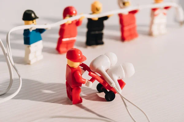 KYIV, UKRAINE - MARCH 15, 2019: Selective Focus of lego figurine carrying earphones in trolley on white table — Stock Photo