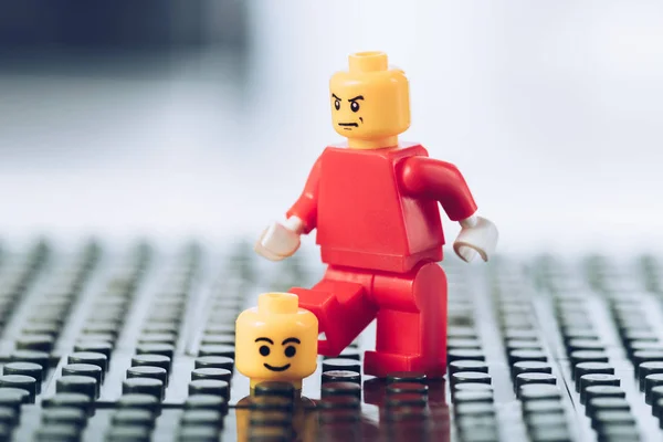 KYIV, UKRAINE - MARCH 15, 2019: Selective Focus of red lego figurine with angy face near head with smiley face on black lego blocks — Stock Photo