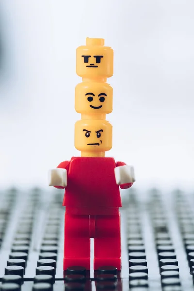 KYIV, UCRANIA - 15 de marzo de 2019: figura de lego rojo con caras indiferentes, sonrientes y enojadas en la cabeza - foto de stock