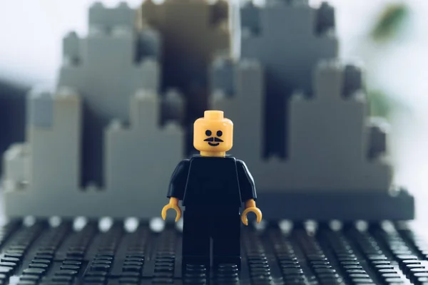 Kyiv, Ukraine - 15. März 2019: selektiver Fokus einer schwarzen Lego-Figur mit Schnurrbart und Smiley-Gesicht vor Gebäuden aus Legosteinen — Stockfoto