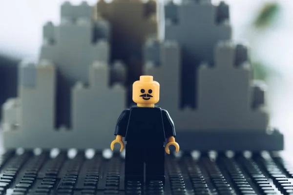 KYIV, UCRANIA - 15 DE MARZO DE 2019: enfoque selectivo de la figura de lego negro con bigote y cara sonriente frente a edificios hechos de bloques de lego - foto de stock