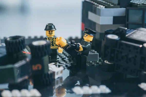 KYIV, UCRANIA - 15 de marzo de 2019: Enfoque selectivo de figuras de policías en uniforme y sombreros arrestando a figura lego en negro - foto de stock