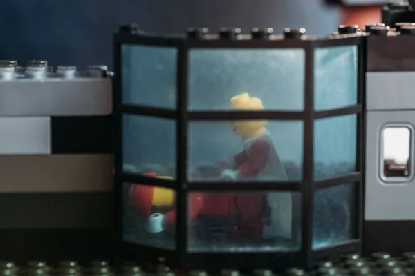 KYIV, UCRANIA - 15 de marzo de 2019: figuras de lego amarillo detrás de la ventana en la casa de bloques - foto de stock