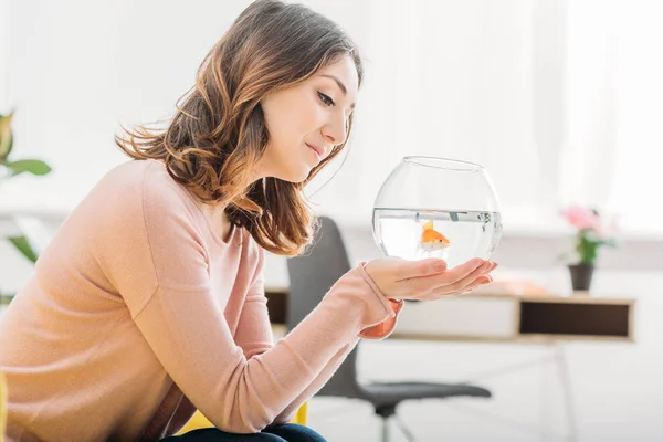 Beautiful smiling woman holding aquarium with gold fish at home — Stock Photo
