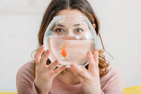 Selektiver Fokus der Frau, die ein Aquarium mit goldfarbenen Fischen hält und in die Kamera schaut — Stockfoto