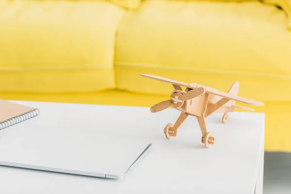 Modelo de avião de madeira perto de laptop na mesa branca em casa — Fotografia de Stock