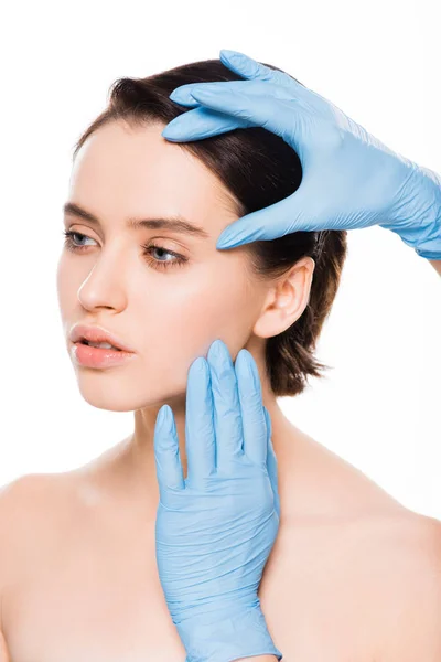 Обрезанный вид пластического хирурга в латексных перчатках трогательное лицо привлекательной девушки изолированы на белом — стоковое фото