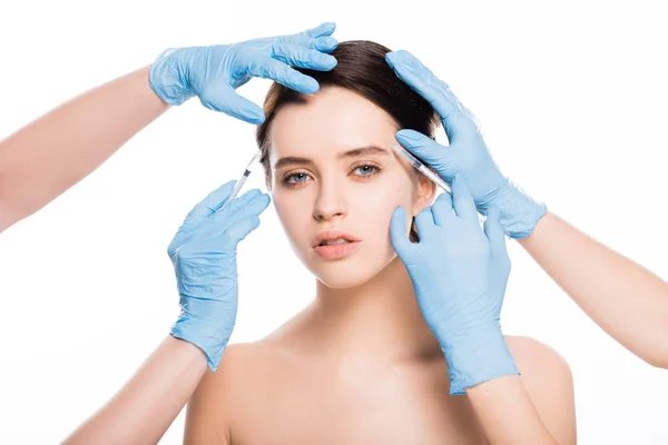 Cropped view of cosmetologists in latex gloves touching face of girl while holding syringes isolated on white — Stock Photo
