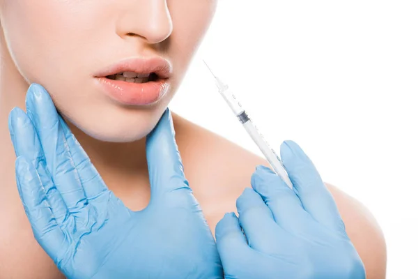 Cropped view of cosmetologist in latex gloves touching face of girl while holding syringe isolated on white — Stock Photo