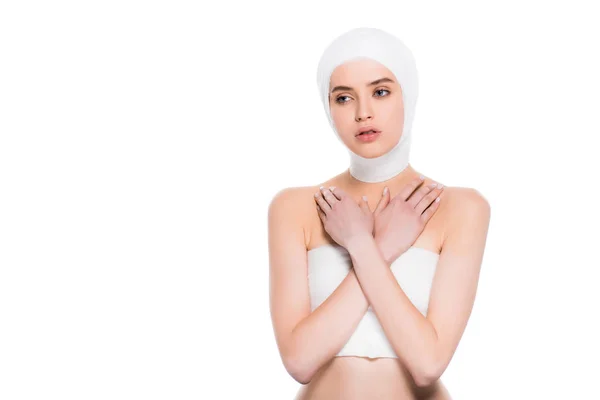 Bela jovem com cabeça enfaixada com braços cruzados após cirurgia plástica isolada em branco — Fotografia de Stock