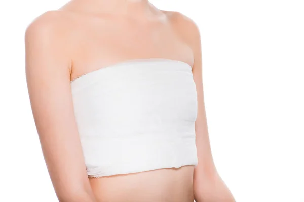 Abgeschnittene Ansicht einer jungen Frau mit bandagierter Brust nach einer plastischen Operation isoliert auf weiß — Stockfoto