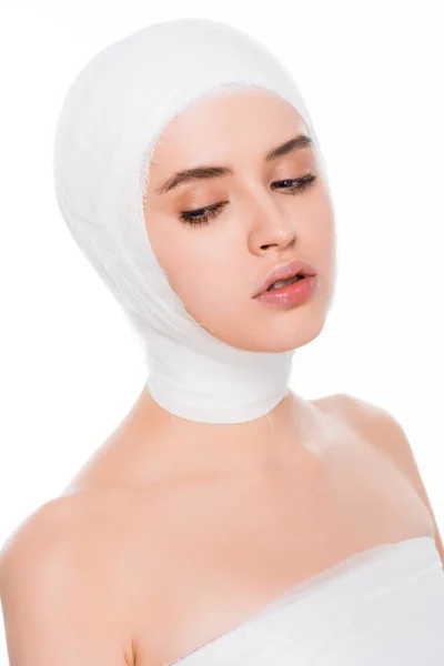 Mujer joven con la cabeza vendada después de la cirugía plástica aislada en blanco - foto de stock