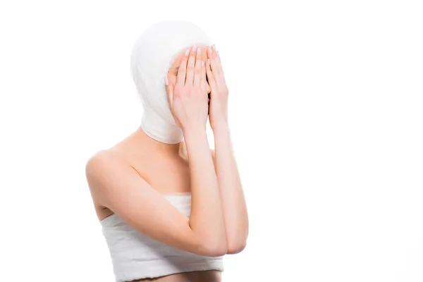 Chica con la cabeza vendada cubriendo la cara con las manos aisladas en blanco - foto de stock