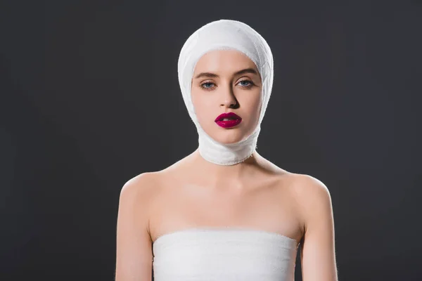 Beautiful girl with bandaged head isolated on grey — Stock Photo