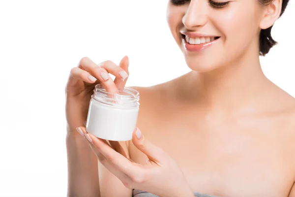 Vista cortada de mulher bonita alegre segurando recipiente com creme cosmético isolado no branco — Fotografia de Stock
