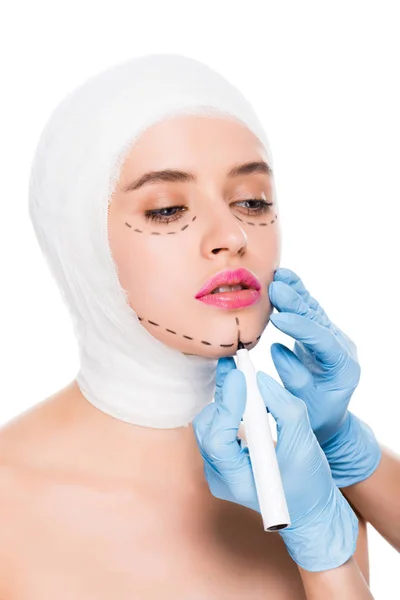 Abgeschnittene Ansicht des plastischen Chirurgen in Latex-Handschuhen mit Filzstift in der Nähe von Frau mit Flecken im Gesicht isoliert auf weiß — Stockfoto
