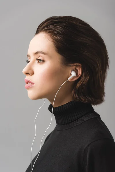 Женщина в черном свитер прослушивания музыки в наушниках изолированы на серый — стоковое фото